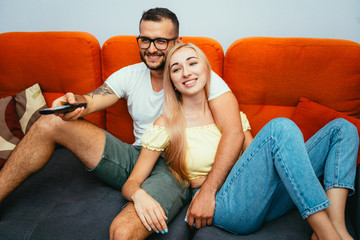 Happy young couple watching TV series together at home