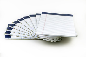 A bunch of white, ruled notepads stacked in a spiral pattern