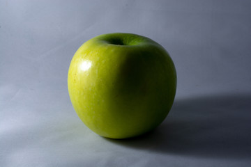 Green Apple in the Shadows/A tasty green apple on a white background with a dark shadow.