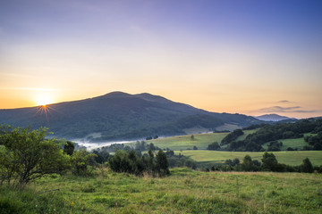 Obraz premium Połonina Caryńska w Bieszczadach o wschodzie słońca. Widok z przełęczy Wyżnej. W oddali Tarnica