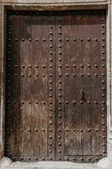 A beautiful ancient scratched wooden door with metal rivets in Spain