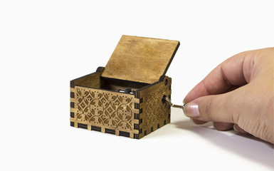Woman's hand playing a music box. Macro of the music box in white background with intricate...