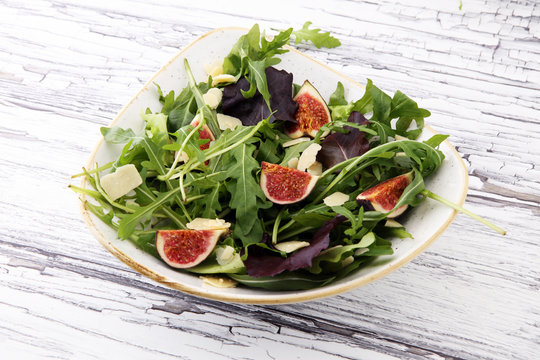 Autumn salad of arugula, figs in a white earthenware plate.