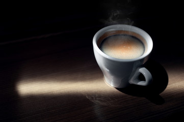 Cup of espresso and coffee beans on wooden background