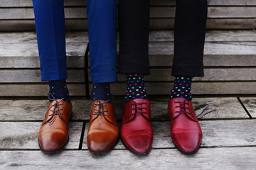 Gay couple sitting on stairs, wearing fancy shoes