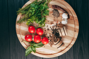 Spices: chili, black pepper, garlic, cumin, coriander, sweet pepper lie on a brown round wooden board on a black table. Place under the text.