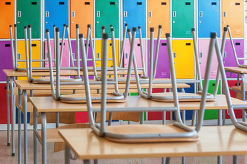 Empty Classroom with colorful lockers and raised chairs on the tables