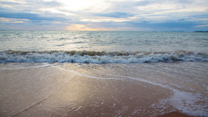 Fototapeta na wymiar Sand beach with sea waves in the sunset.