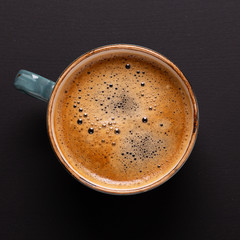 Cup of coffee on black background. Copy space. Square. Top view. Flat lay.