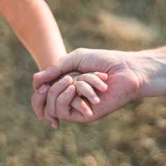 parent holds the hand of a small child. Father holds the child by the hand. close-up. In the background. Support on the way.