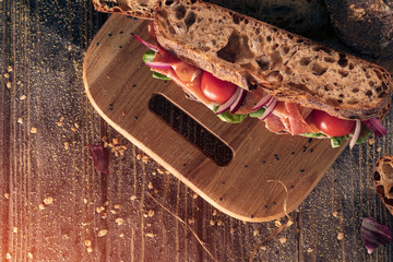 top view of fresh sandwich with tomato and ham on wood;