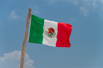 Mexican flag over blue sky in Tulum, Mexico.