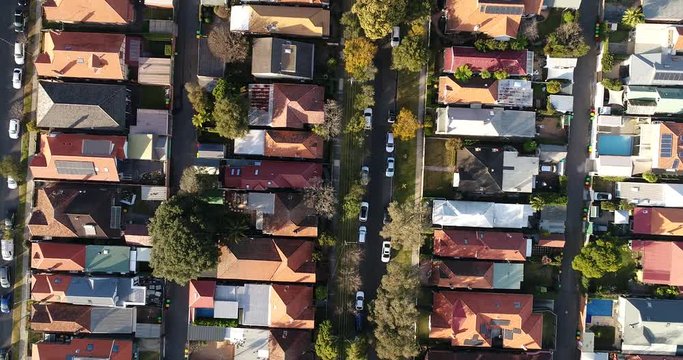 Residential houses on quiet street of Lower North Shore suburb in Sydney seen from above over lanes, yards and parked cars.
