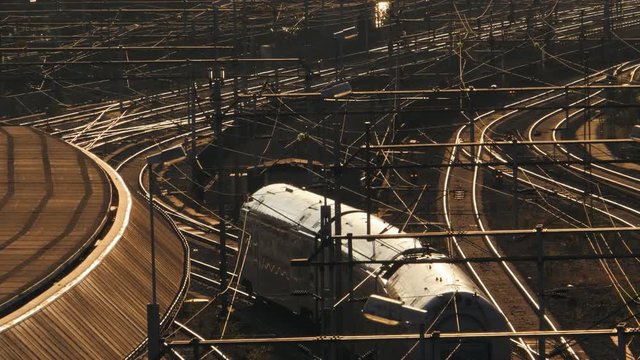 AERIAL SHOT of a gray train slowly moving on its tracks in a lovely sunset in Stockholm, Sweden. Filmed in SLOW MOTION.