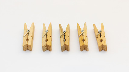 Isolated wooden clothes pegs lying side by side on a white background