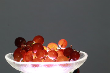 Close up transparent red grape fruits on small glass dish 