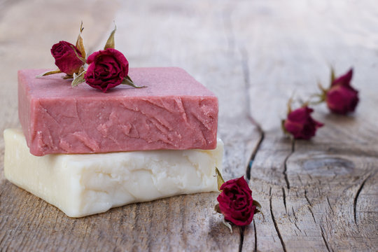 Natural hand made soap with dry pink roses on vintage wooden background spa setting