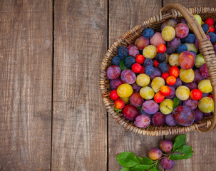 variety of plums on wooden surface