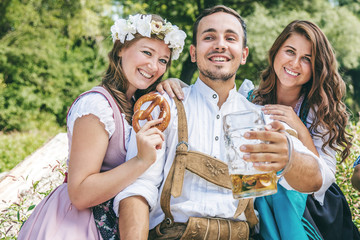Freunde in trachtenmode entschpannen an der Isar