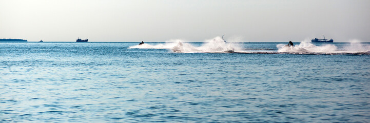 Obraz premium people ride a water motorcycle in the sea, panorama