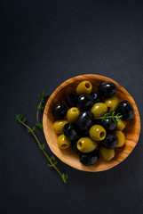 olives in a wooden bowl on black surface
