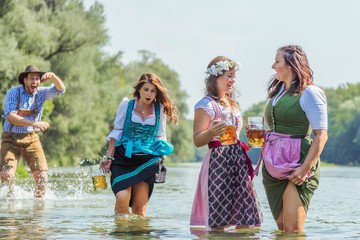 Freunde in trachtenmode entschpannen an der Isar