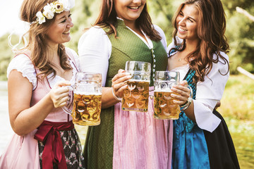 Oktoberfest Freunde in Lederhosen und Dirndl trinken Bier an der Isar