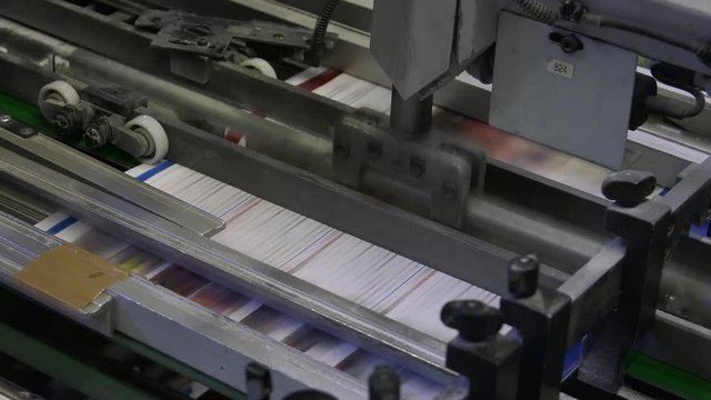 In the press office the machine moves newspapers and magazines on the production tape. Closeup