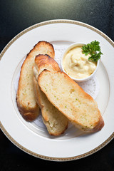 Close up top view garlic  bread baked sliced with mayonnaise and parsley on white plate