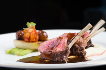 close up lamp rack pored by stocks with asparagus and sliced tomato, cucumber, onion, apricot, carrot on white plate lighted by studio light  