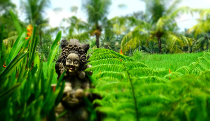 Bali statue sits in lush gardens.