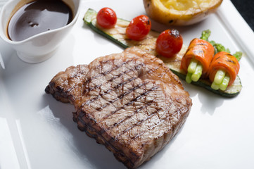 Close up Hida beef steak with grilled tomato, carrot, cucumber and asparagus on white plate