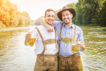 Oktoberfest Freunde in Lederhosen und Dirndl trinken Bier an der Isar