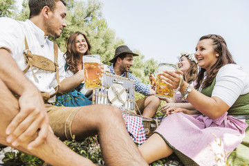 Oktoberfest Freunde in Lederhosen und Dirndl trinken Bier an der Isar