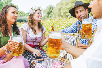 Oktoberfest Freunde in Lederhosen und Dirndl trinken Bier an der Isar
