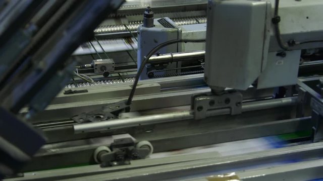 In the press office the machine moves newspapers and magazines on the production tape. Closeup