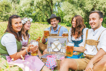 Oktoberfest Freunde in Lederhosen und Dirndl trinken Bier an der Isar