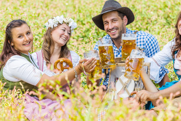 Oktoberfest Freunde in Lederhosen und Dirndl trinken Bier an der Isar