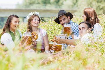 Oktoberfest Freunde in Lederhosen und Dirndl trinken Bier an der Isar