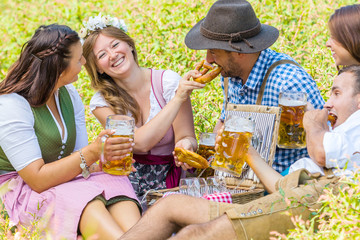 Oktoberfest Freunde in Lederhosen und Dirndl trinken Bier an der Isar