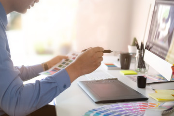 Graphic designer working with digital tablet and mouse pen on table and morning light.