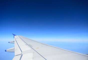 Fototapeta premium Wing of an airplane flying and Blue sky background with beautiful clouds in sky. View from the window airplane flying.