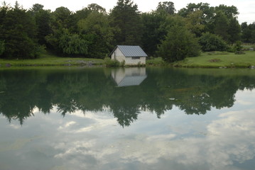 Fototapeta na wymiar Reflection of a shed house on a pond 