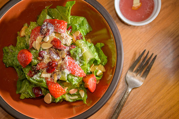 Fresh salad with strawberries in bowl on table