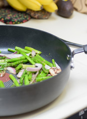 Vegetables with mushrooms in frying pan on table