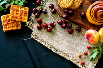 Homemade cinnamon buns in glaze on a dark plate with berries