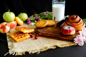Homemade cinnamon buns in glaze on a dark plate with berries