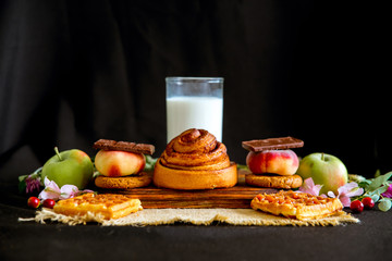 Homemade cinnamon buns in glaze on a dark plate with berries