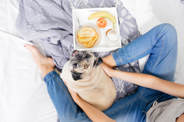 Young woman with her dog in a bed. Breakfast in bed