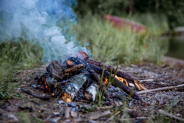 Beautiful campfire in the evening at lake. Fire burning in dusk at campsite